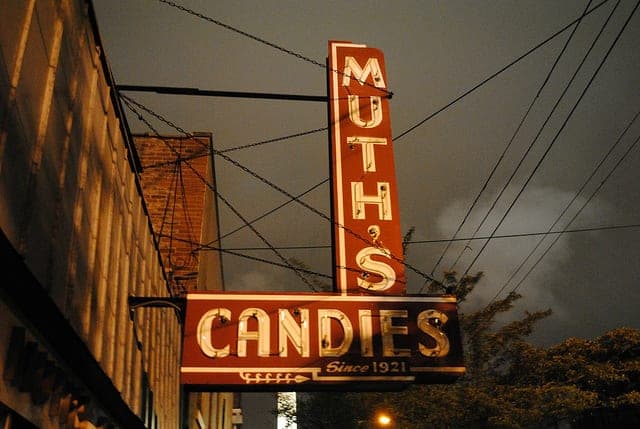 The Muth's Candies neon sign on Market Street, Louisville, lit at dusk.